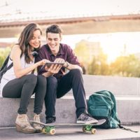 casal feliz a rir enquanto está sentado com uma ponte ao fundo