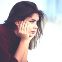 lonely young beautiful woman sitting on bench in the park