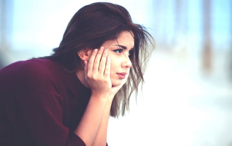 lonely young beautiful woman sitting on bench in the park