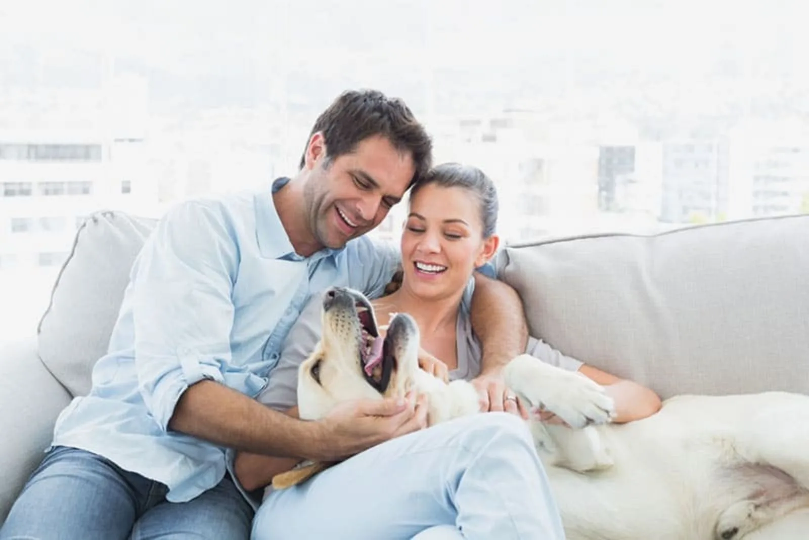 a man and a woman sit and play with a dog