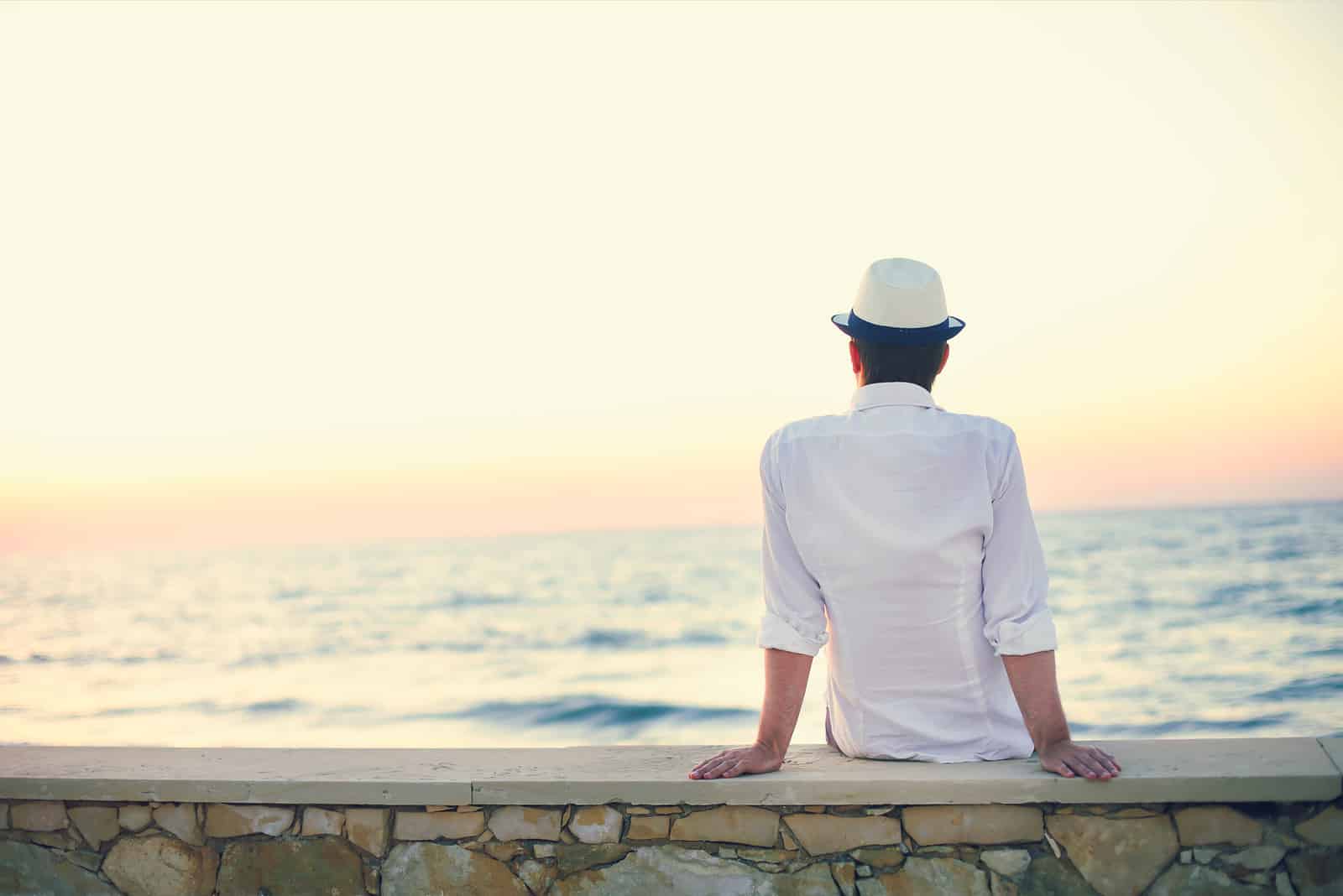 un uomo immaginario siede sul muro e guarda il mare