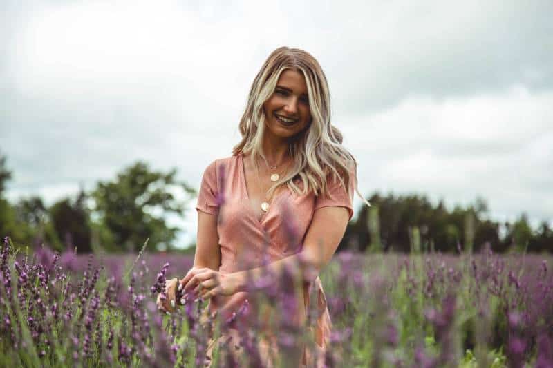mujer rubia en medio de un campo de flores moradas