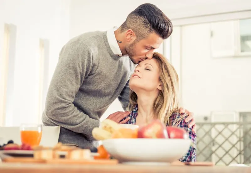 couple having breakfast with wife and kissing her