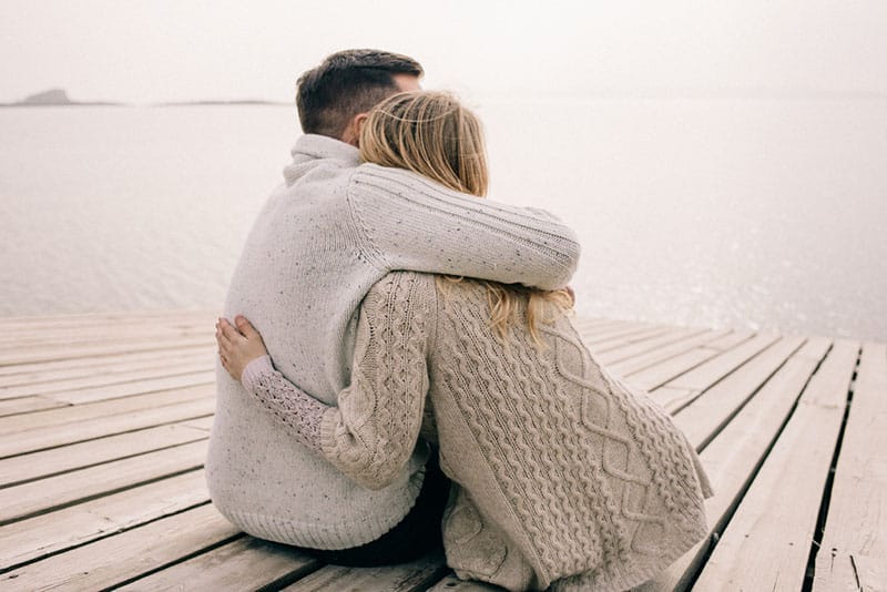 lovely couple hugging on a pier by the ocean 