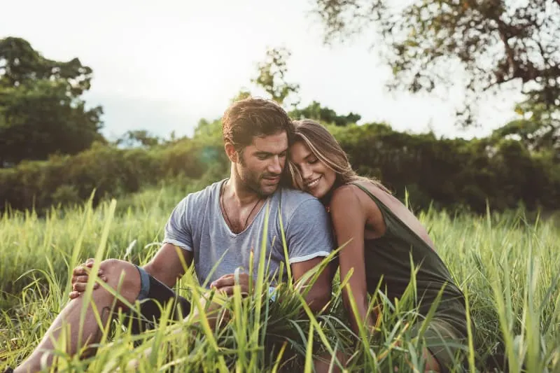couple hugging while sitting on grass