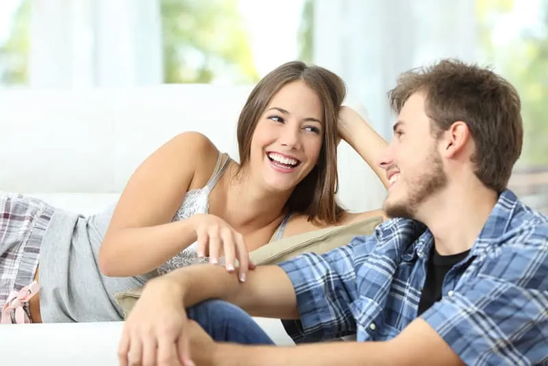 cute and young couple talking on the couch 