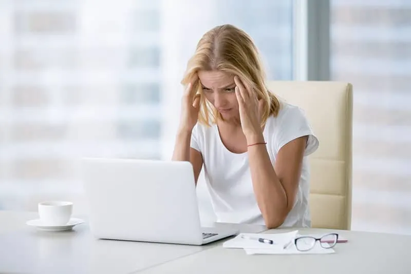 frustrated blonde business woman in the office by her laptop