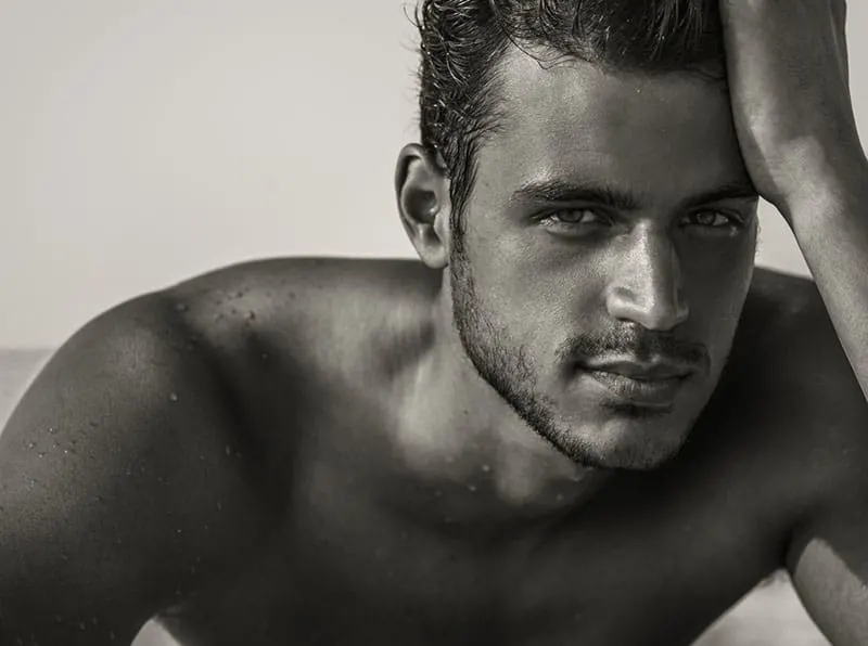 black and white picture of a handsome shirtless man on the beach
