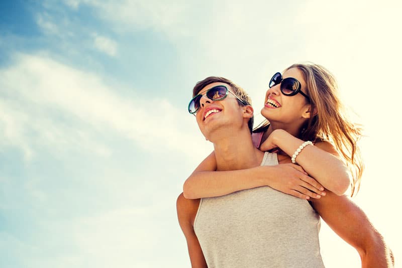 happy young couple piggyback outside having fun