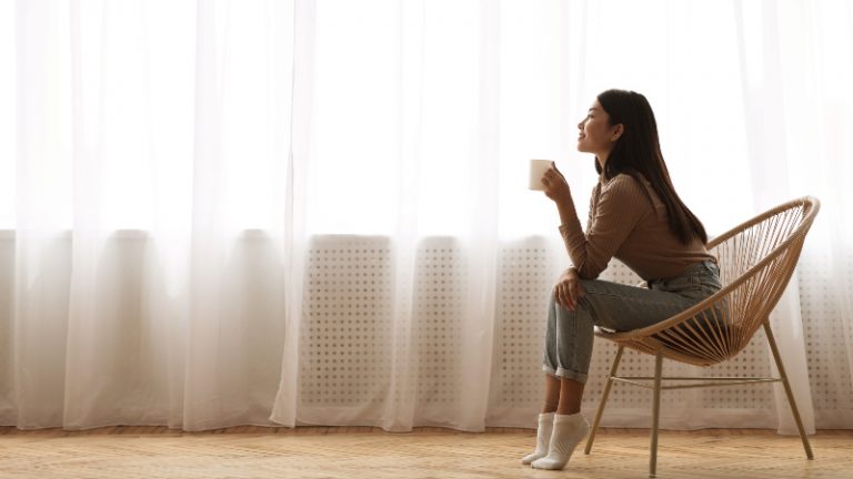 chica sentada en una silla cerca de una ventana