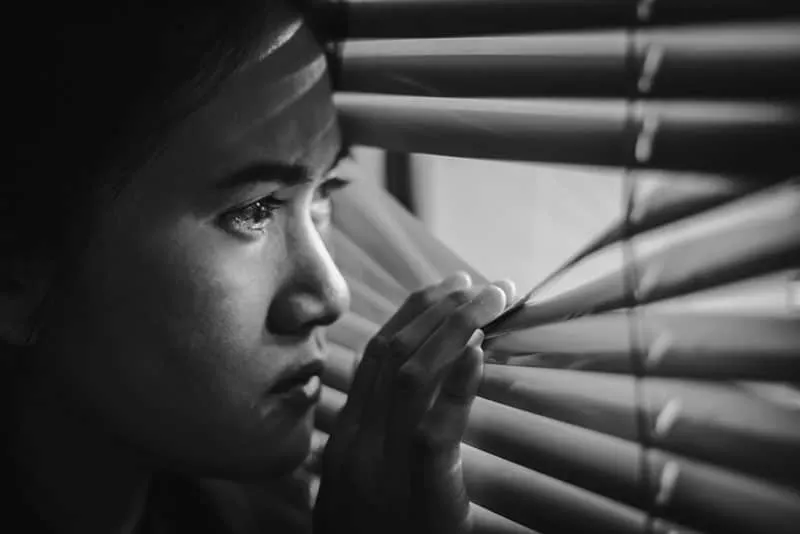 black and white picture of a jelous asian woman looking through th window 