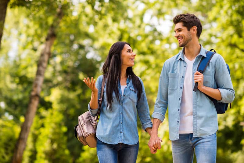 lovely couple holding hands and smiling while enjoying a walk in the nature