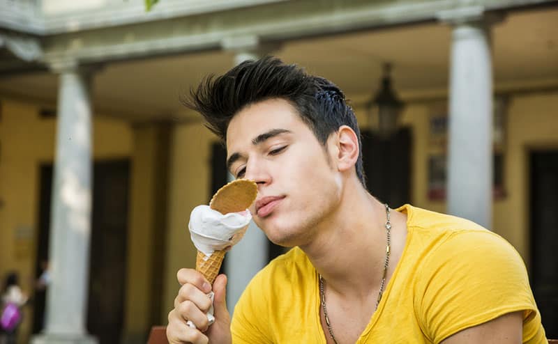 uomo affascinante in camicia gialla che mangia un gelato