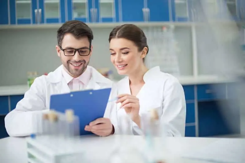 portrait of smiling scientists writing in notepad in lab