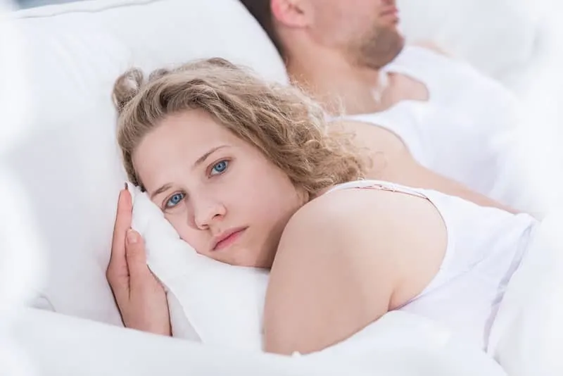 sad young couple not talking to each other while laying in the bed