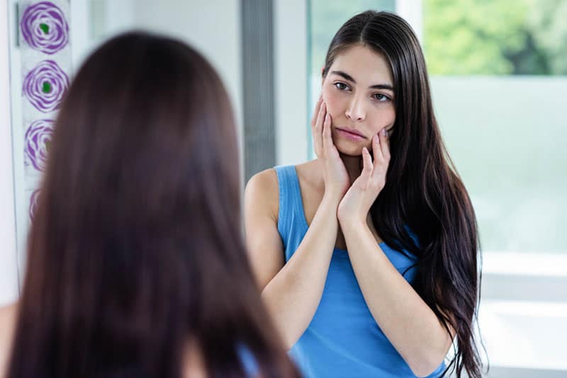 sad woman in mirror looking at herself