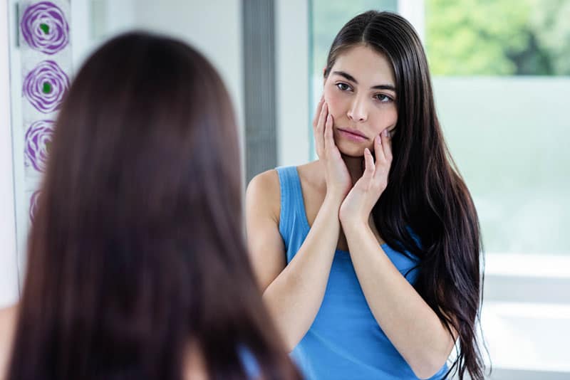 mujer triste en el espejo mirandose a si misma