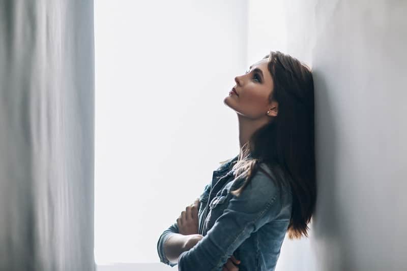 sad lonely woman leaning on a white wall