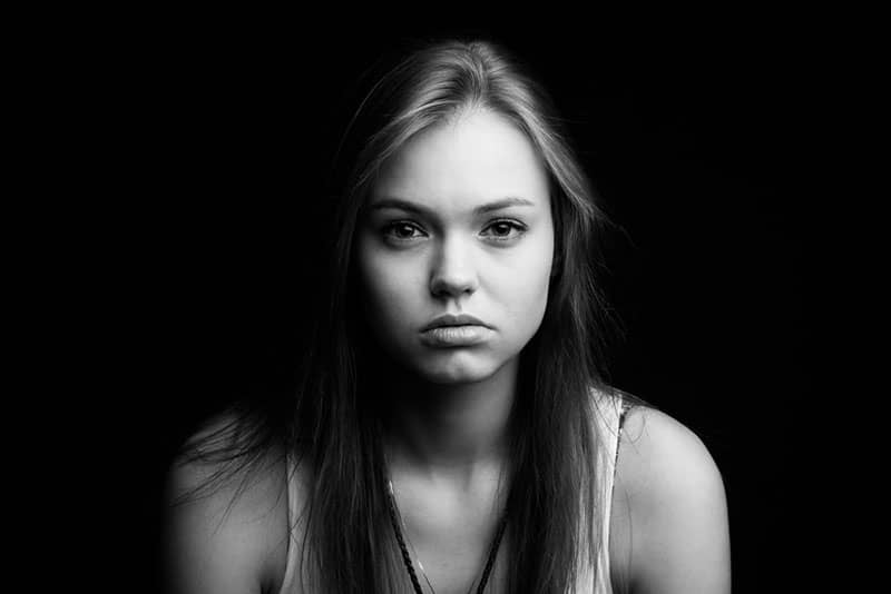 foto en blanco y negro de una mujer rubia triste en la oscuridad