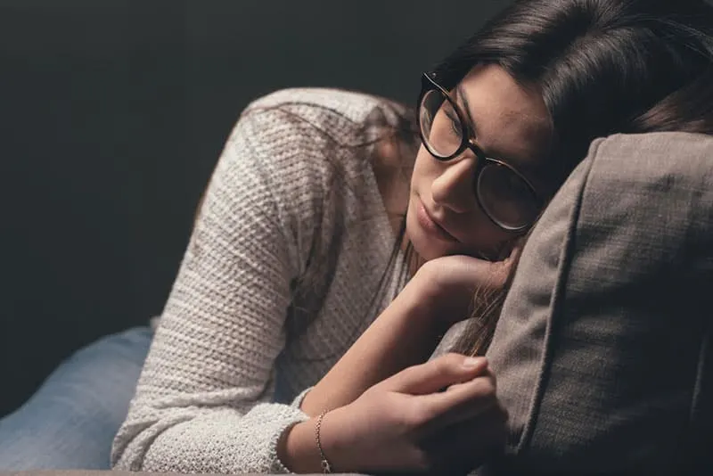 sad woman with glasses sitting on the couch 