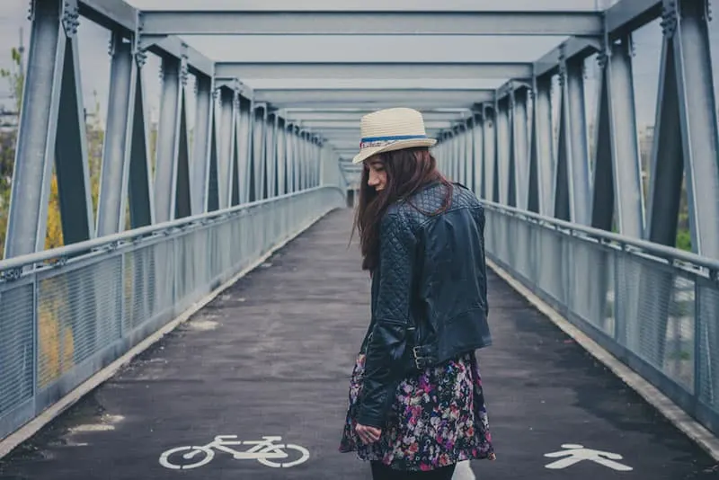 sad young redhead woman standing on the bridge