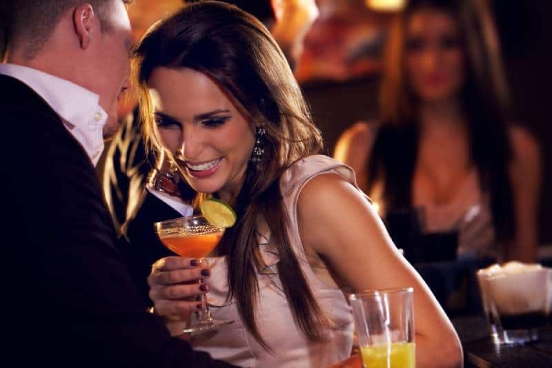 pareja sonriente en el bar disfrutando del cóctel
