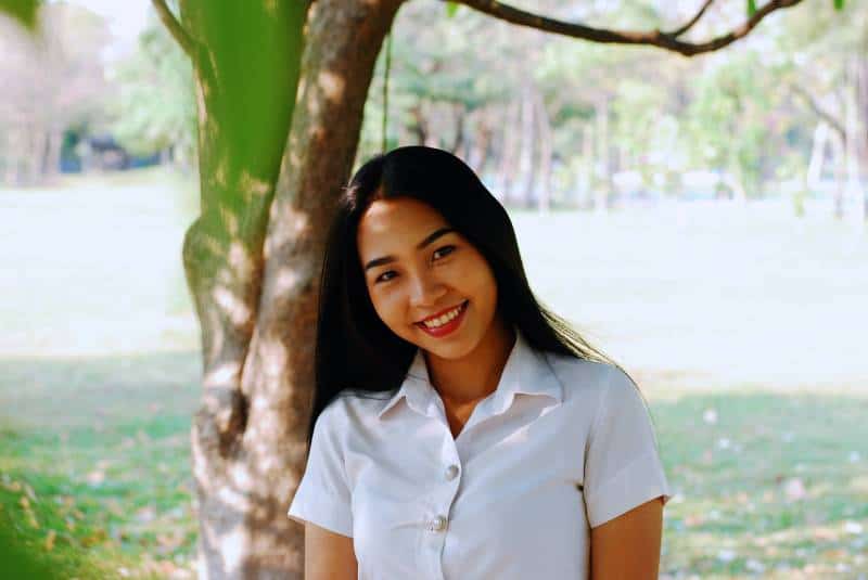 smiling woman standing next to tree