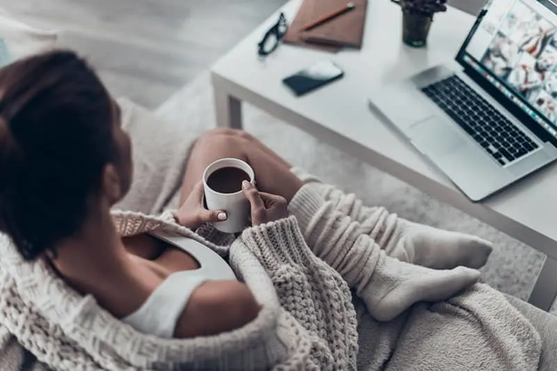woman sitting on a couch and enjoying cup of fresh cofee 