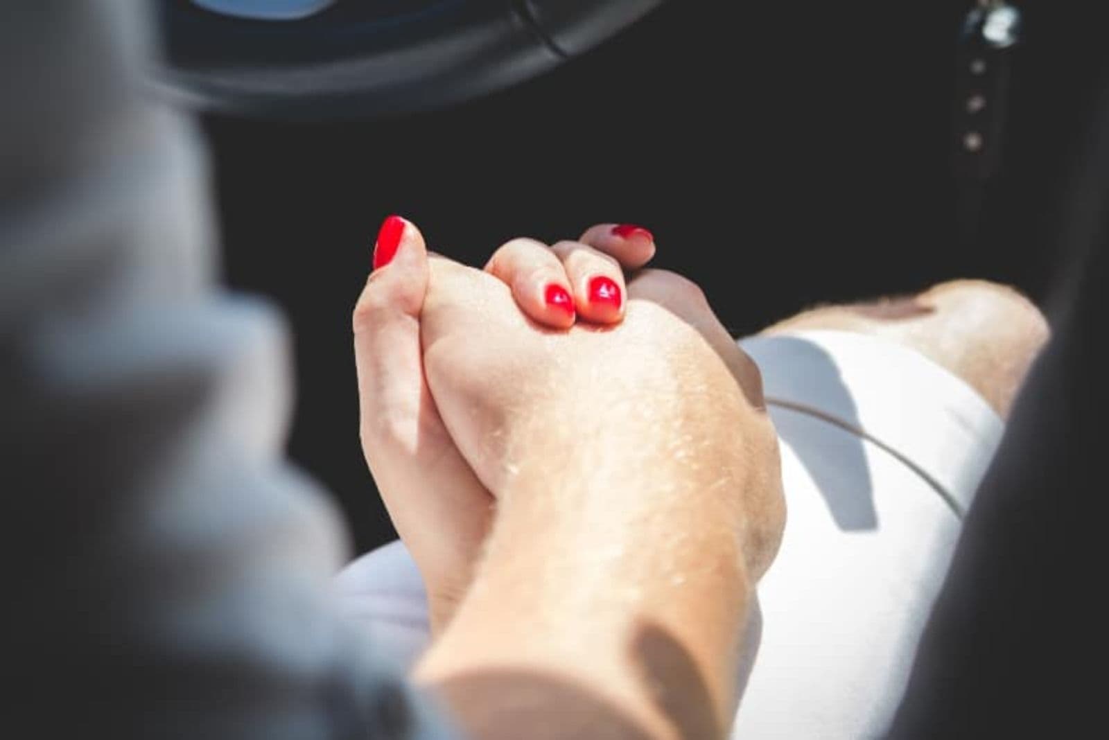 woman with red nail polish holding guy for hand