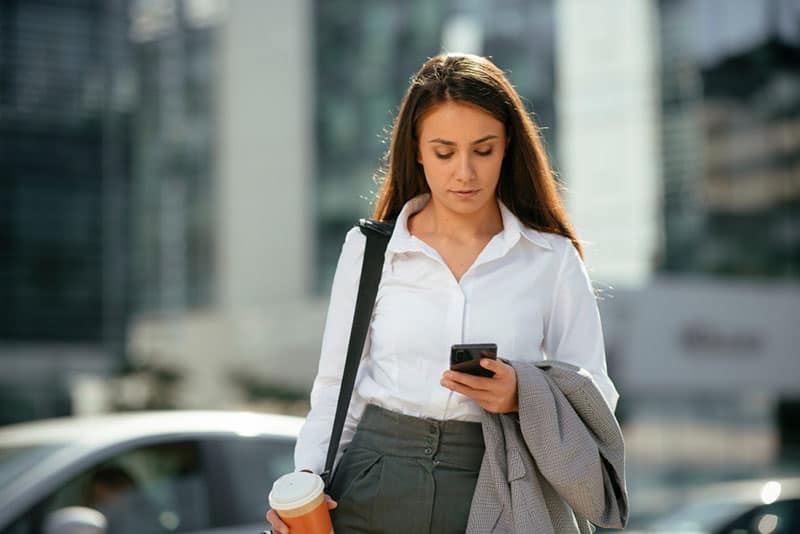 mulher de negócios a caminhar com o telemóvel na mão