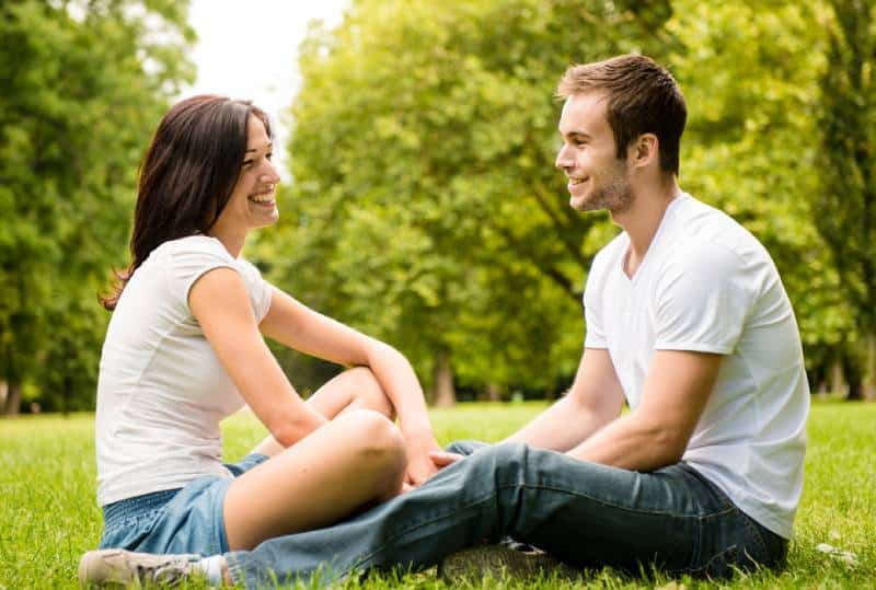 young couple sitting on grass in nature