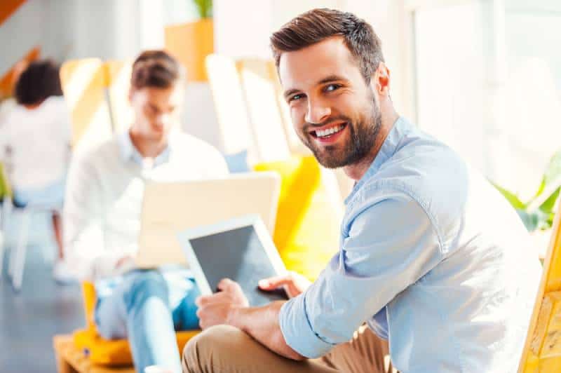 young man holding tablet and smiling