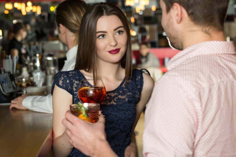 mujer joven mirando fijamente a los ojos de hombre joven en el bar