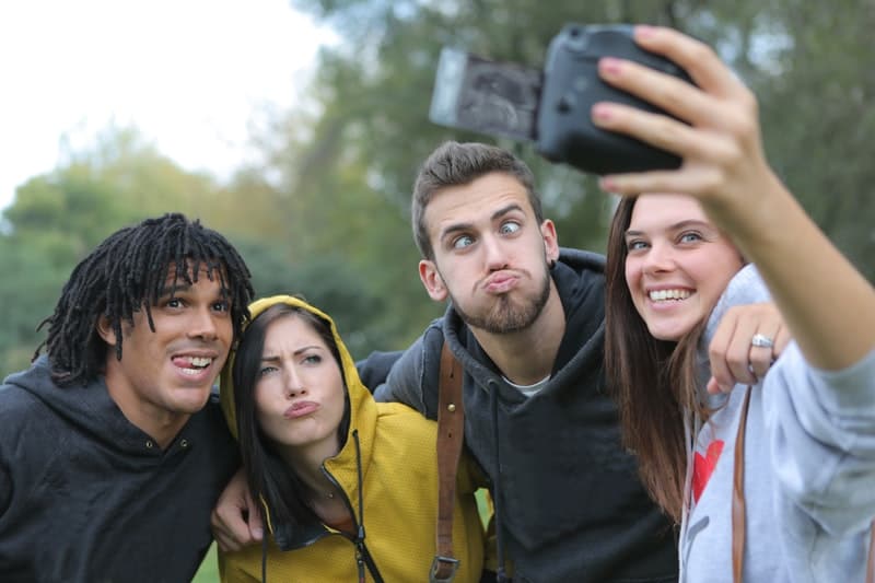 4 personas haciendo una foto con una cámara instantánea