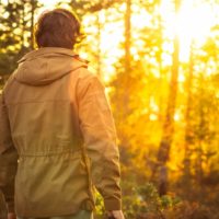 young man standing alone in forest