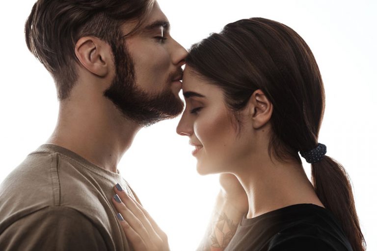 man kissing woman in forehead