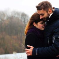 encantadora pareja abrazándose en la naturaleza junto al agua