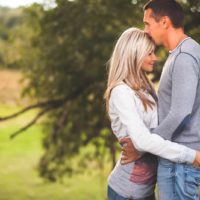 a loving couple hugging and kissing under a tree