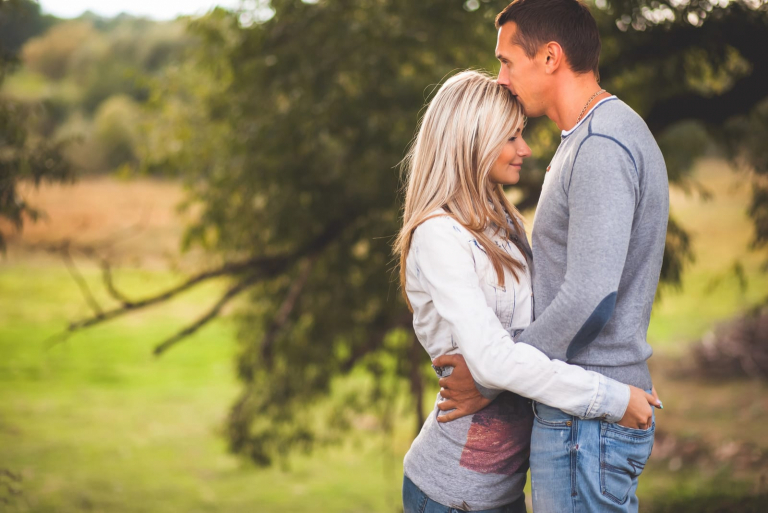 a loving couple hugging and kissing under a tree