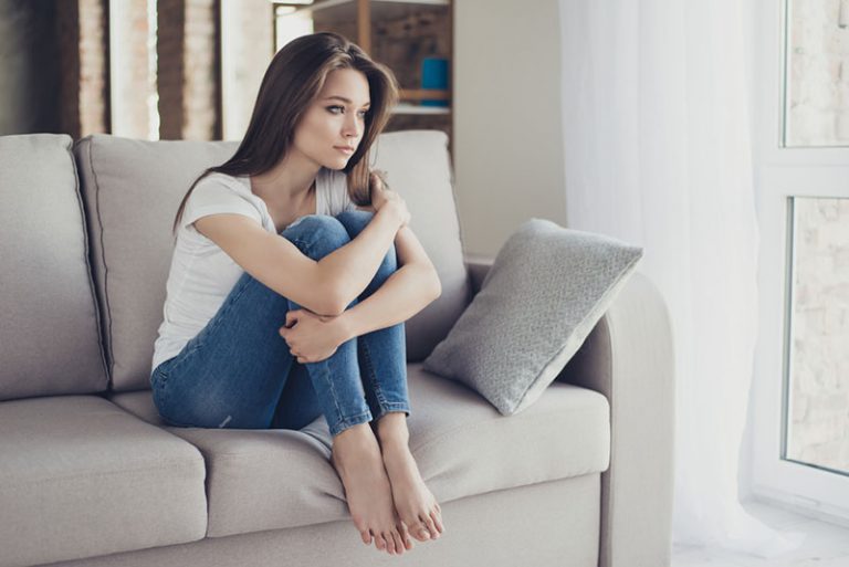mujer triste sentada en el sofá