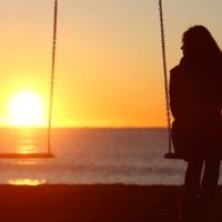 sad woman sitting alone on the swingset