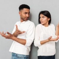 confused couple looking at each other indoors