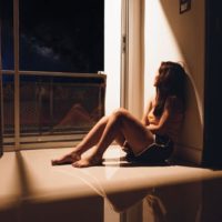 sad and lonely young woman sitting in dark