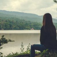 mujer triste sentada junto al lago