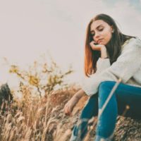 worried girl sitting on a stone outside