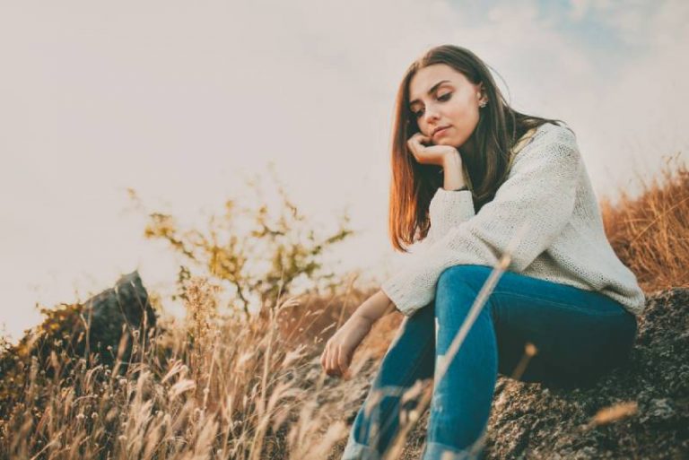 worried girl sitting on a stone outside