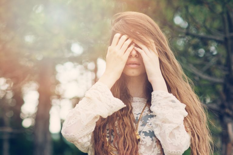 sad woman standing with hands on the eyes