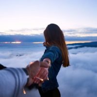 man holding woman's hand on top of hill