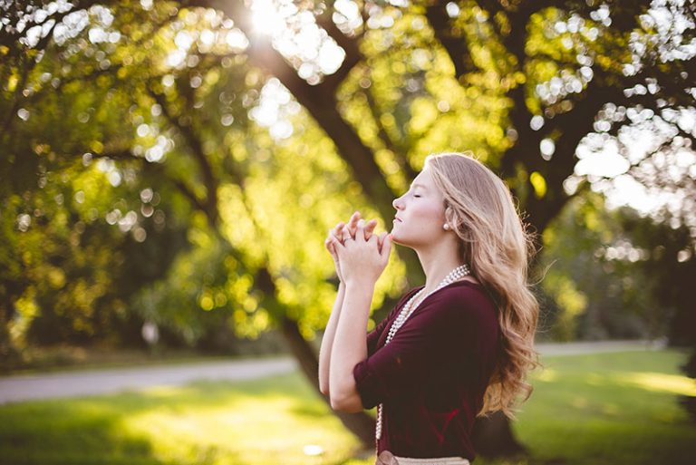 blond woman praying in the nature