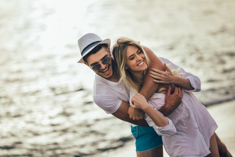 hombre abraza a mujer de espaldas junto al mar